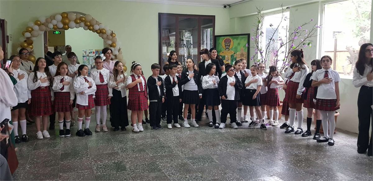 დაწყებითი კლასების მოსწავლეები ხელები გულზე, სკოლის ღონისძიებაზე