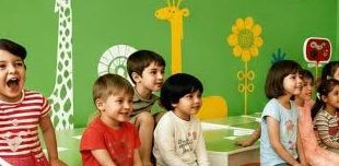 Preschool-ის ჯგუფი საკლასო ოთახში, კედელზე დახატული ჟირაფი